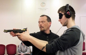 Fotografia: Uczestnik turnieju celuje do tarczy wspierany przez czujne oko i pomocną dłoń instruktora